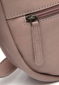 Borsa in pelle rosa chiaro con finitura testurizzata, dotata di chiusura a zip, cuciture a contrasto e un'etichetta in tessuto attaccata alla cerniera.