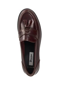 Burgundy leather slip-on shoe with a flat sole, featuring a matching tassel detail and a branded insole labeled "Dune London."