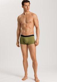 Boxer briefs para hombres en verde olivo con una cinturilla negra, fabricados en un material suave, con un ajuste ceñido y un diseño de bolsa de soporte.