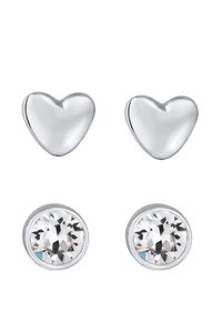 Boucles d'oreilles en argent en forme de cœur et clous en cristal transparent. Les boucles en forme de cœur ont une finition lisse, tandis que les clous en cristal présentent des détails facettés.