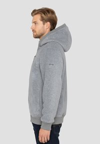 Grijze capuchontrui met een zachte textuur, geribbelde manchetten en tailleband. Voorzien van een logo op de linkerarm en een zak met ritssluiting.