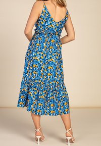 Modré květinové šaty s žlutými akcenty, vrstevnatým lemem, nastavitelnými špagetovými ramínky a vypasovaným pasem. Lehká tkanina s jemnou texturou.