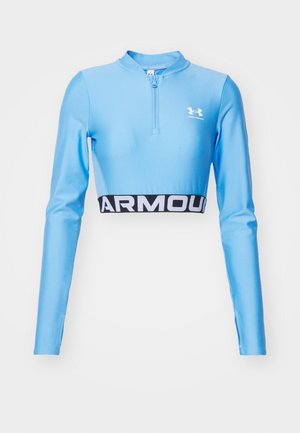 Top sportivo crop blu a maniche lunghe con collo a mezza zip. Presenta una fascia nera con la scritta "ARMOUR" in lettere bianche all'orlo. Realizzato in un materiale elastico.