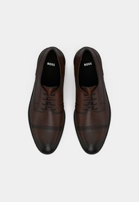 Καφέ δερμάτινα παπούτσια με λεία επιφάνεια, με σχέδιο κορδονιών, διακοσμητικές λεπτομέρειες brogue και μαύρη λαστιχένια σόλα.