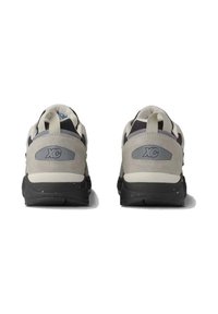 Scarpe da ginnastica grigio chiaro con accenti neri, dotate di una tomaia testurizzata, suola nera spessa e linguette sul retro. Logo "XC" visibile su ciascun tallone.