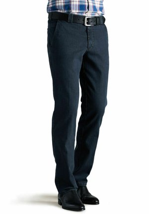 Donkerblauwe denim jeans met een rechte pasvorm, voorzien van voorzakken en een zwarte riem. Ggedragen met zwarte dress boots.