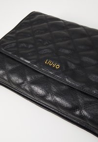 Clutch in pelle trapuntata nera con logo "LIUJO" dorato. Presenta un motivo a diamante e una texture liscia, progettata per un'archiviazione elegante e uno stile raffinato.