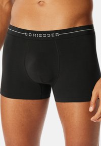 Boxer neri attillati, con una comoda cintura liscia impreziosita dal logo "SCHIESSER" e dettagli di texture discreti sul tessuto.
