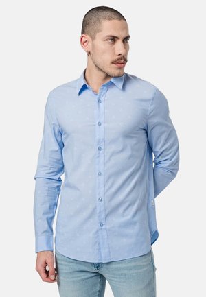 Camisa de botones azul claro hecha de una tela con un patrón sutil, con mangas largas, cuello y corte regular.