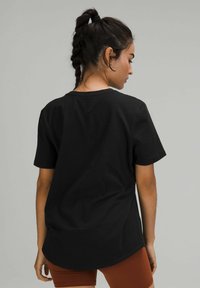 Svart kortärmad T-shirt med rund halsringning, tillverkad av mjukt tyg, med rundad nederkant och minimalistisk design.