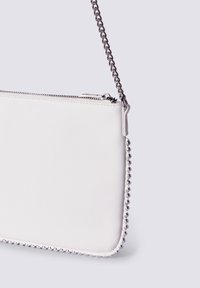 Borsa a mano sintetica bianca con texture liscia, chiusura con zip e accentuazione metallica a forma di pallina lungo il bordo; presenta una tracolla in catena argentata.