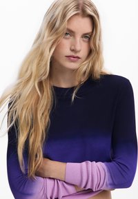 Svetr s dlouhými rukávy s přechodem barev od tmavě modré po fialovou, s růžovými žebrovanými manžetami. Měkký materiál a přiléhavý střih.