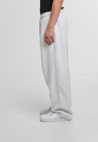 Light grey sweatpants made of soft material, featuring an elastic waistband, side pockets, and a relaxed fit. Flat seams along the sides.
