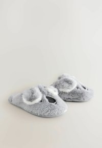 Grå pelse slippers med hvide accenter, rundede former, åben tå og blød tekstur. Har lette pom-poms på toppen til dekoration.