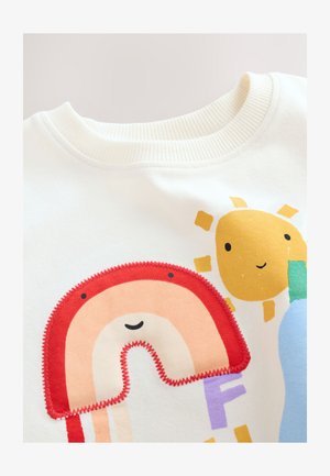 Valge dressipluus, millel on värvikas vikerkaare kujutis punaste õmblustega, kollane päike ning mängulised kirjastiilid lillades ja rohelises.