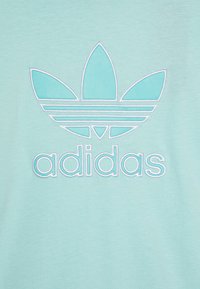 Ανοιχτό μπλε βαμβακερό t-shirt με μεγάλο κεντητό λογότυπο Adidas σε ταιριαστά χρώματα, με σχέδιο καλλιγραφικών φύλλων και οριζόντιες γραμμές.