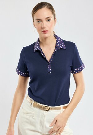 Polo shirt bleu marine avec col et poignets à motifs, à manches courtes, avec une patte de boutonnage à trois boutons, et fabriqué dans un tissu lisse et texturé.