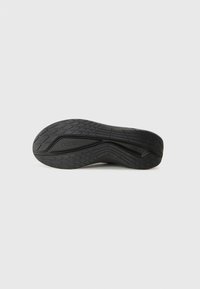 Black rubber shoe sole with a textured, patterned surface, featuring ridges for traction and a slight curve at the heel.