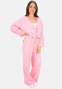 Helles rosa Zweiteiler-Set mit einer lockeren, kurz geschnittenen Bluse mit gebundenem Bund und weit geschnittenen Hosen mit dekorativem Saum.