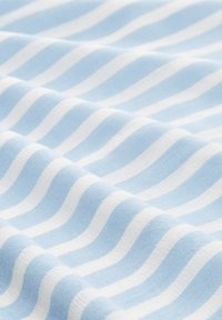 Tela de color azul claro con rayas blancas en forma ondulada. El material de algodón parece suave con una textura lisa, exhibiendo un patrón rítmico.