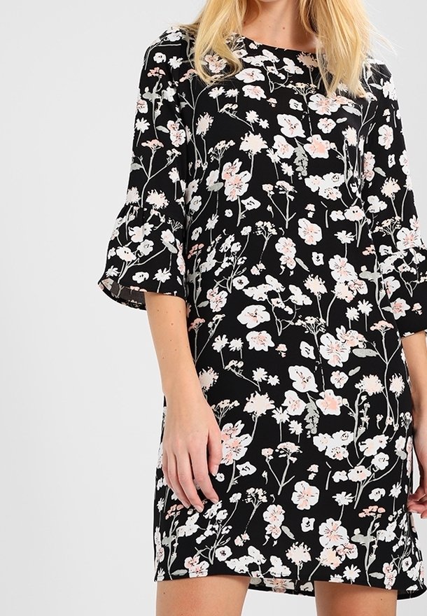 Černé květinové šaty s krátkými rozšířenými rukávy, jemnými vzory růžových a bílých květin a volným střihem pro snadnost pohybu.
