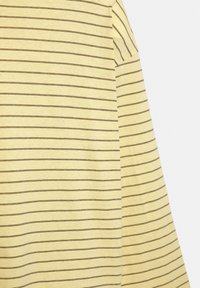 Camicia di cotone gialla con righe orizzontali marroni, maniche corte e una texture morbida. Il design è semplice e informale.