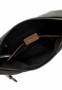 Black zippered bag interior featuring a smooth fabric lining, a brown leather label, and minimalistic design with a single compartment.