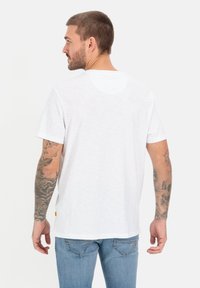 Hvid kortærmet t-shirt i letvægtsstof med rund halsudskæring og en lille labeldetalje nær sømmen.