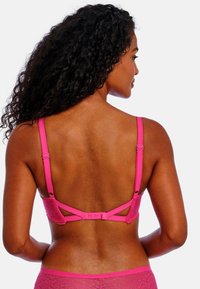 Sostenedor de encaje rosa con tirantes ajustables, cierre de gancho y ojo en la parte posterior, y diseño con recortes para un detalle adicional. Textura suave con patrones intrincados.