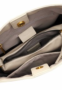 Leather handbag in cream with gold hardware. Features a zippered compartment and multiple pockets in a soft, textured finish.