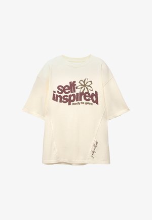 Kermanvärinen puuvillahihaton t-paita, jossa on lyhyet hihat, ja jossa on teksturoitu "itsekäynnistynyt" graafinen kuvio ruskeana ja oliivinvihreänä, sekä pieni brodeerattu yksityiskohta helmaa.