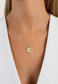 Collier en pendentif en or avec une forme texturée et irrégulière, comportant des accents de pierres précieuses colorées, suspendu à une délicate chaîne en or.