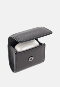 Étui en cuir noir avec fermeture à rabat, doté d'un bouton argenté, conçu pour contenir en toute sécurité un étui de charge blanc à l'intérieur.