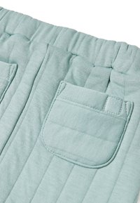 Lichtblauwe stoffen broek met ribbeltextuur, elastische tailleband en twee voorzakken. Kenmerkt zich door een klein reliëflogo op de zak.