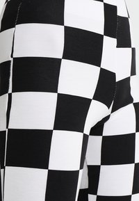 Black and white checkered leggings made of stretch fabric, featuring a bold pattern of alternating squares and precise stitching details.