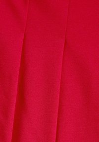Tissu rouge avec une texture lisse, présentant un tissage à plat et des lignes de couture visibles. La couleur est vive et uniforme sur toute la surface.