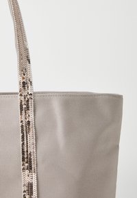 Sivá plátená taška s textúrovaným povrchom a flitrovým popruhom, ktorý obsahuje striedajúce sa kovové odtiene.