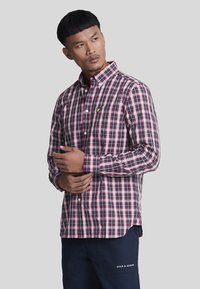 Camicia a maniche lunghe a quadri rossi e navy con colletto pieghevole, logo giallo piccolo sul lato sinistro del petto. Tessuto in misto cotone.