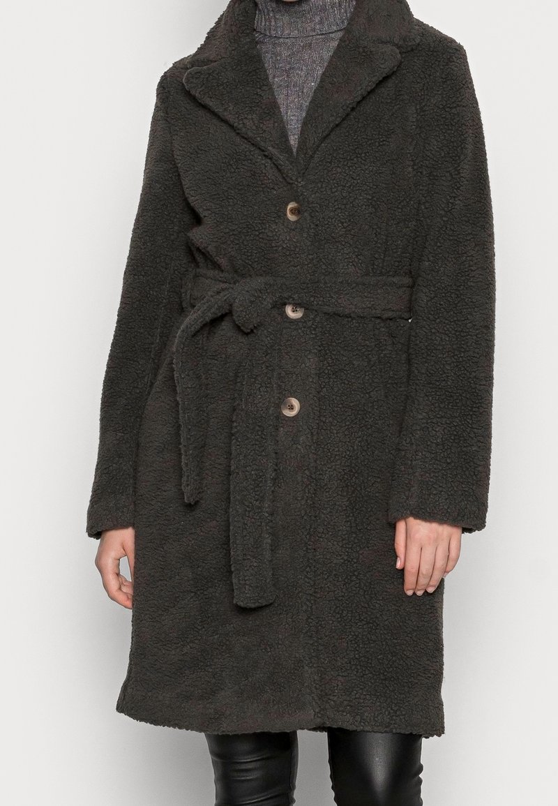 Abrigo de un gris oscuro, esponjoso, con cuello chal, dos botones en la parte frontal y un cinturón en la cintura. Presenta mangas largas y una tela suave con textura.