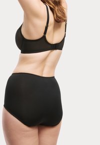 Zwarte bh met verstelbare bandjes, van gaas materiaal en gouden hardware. Hoge zwarte onderbroek met een gegolfde rand, gladde textuur.