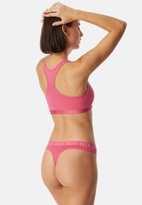 Růžový sportovní podprsenka a tanga set vyrobený z měkké směsi bavlny. Racerback design, elastický pás s logem "ELLE", hladký povrch a přiléhavý střih.