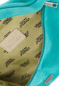 Turkusowa torebka z zamszu z zamkiem błyskawicznym. Wnętrze wykończone beżowym materiałem z nadrukiem logo "Venezia" oraz skórzaną metką.