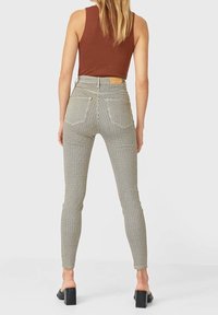 Zwart-witte, getailleerde geblokte broek met een hoge taille, vijf zakken en een bruine leren label aan de achterkant. Soepele stof en enkellengte.