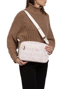 Borsa a spalla bianca con motivo a logo in rilievo, hardware dorato e tracolla crema. Texture liscia e forma rettangolare.