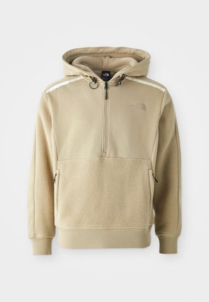 Sudadera beige con media cremallera, cuerpo de forro polar y tela suave en los hombros. Incluye cordones ajustables y bolsillos con cremallera.