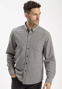 Czarna i biała koszula z długim rękawem w kratę, z klasycznym kołnierzykiem i jedną kieszenią na piersi. Z tkaniny bawełnianej o delikatnej fakturze.