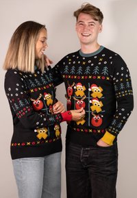 Black knit sweaters with festive designs, featuring multicolored reindeer and Christmas motifs, with red and yellow cuffs.