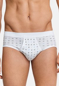 Weiße Unterhose aus weichem Stoff, mit einem geometrischen Muster aus winzigen bunten Quadraten in Hellblau, Grau und schwarzen Akzenten.