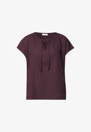Blouse prune foncée à manches courtes avec encolure ronde, ouverture en forme de goutte à l'avant et fermeture par lien fin sur fond blanc.