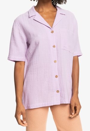Short-sleeve lavender button-up shirt with pointed collar and chest pocket worn by person with tan textured pants.